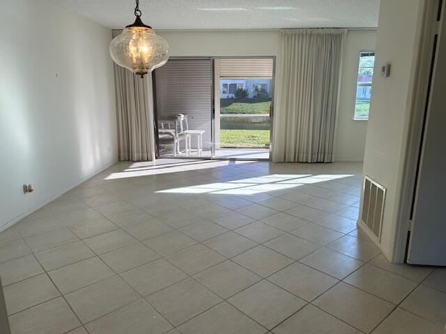 tiled empty room featuring a textured ceiling