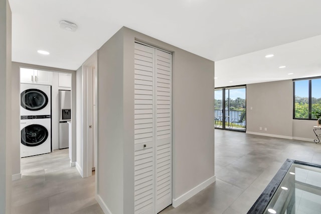 hall featuring stacked washer and dryer and a wall of windows