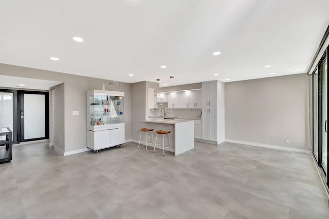 kitchen with sink, white cabinets, a kitchen breakfast bar, hanging light fixtures, and kitchen peninsula