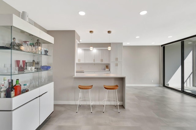 kitchen featuring a breakfast bar, pendant lighting, white cabinets, expansive windows, and kitchen peninsula