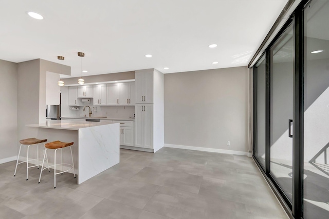 kitchen with hanging light fixtures, tasteful backsplash, white cabinets, a kitchen bar, and kitchen peninsula