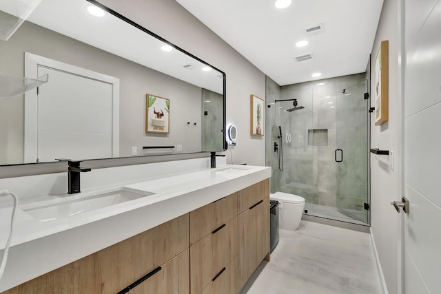 bathroom featuring vanity, a shower with shower door, and toilet