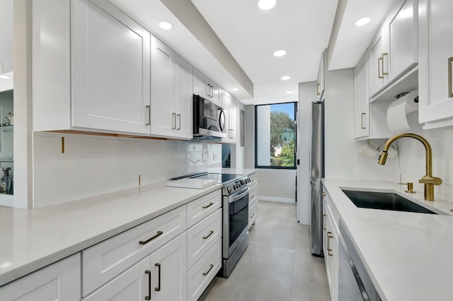 kitchen featuring appliances with stainless steel finishes, sink, white cabinets, and light stone counters