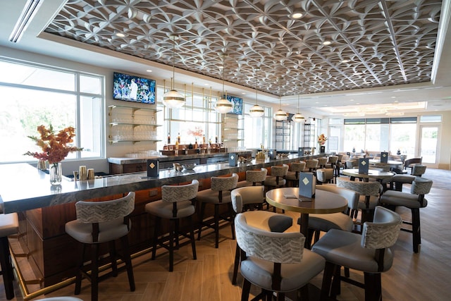 dining area featuring bar, a tray ceiling, and parquet flooring