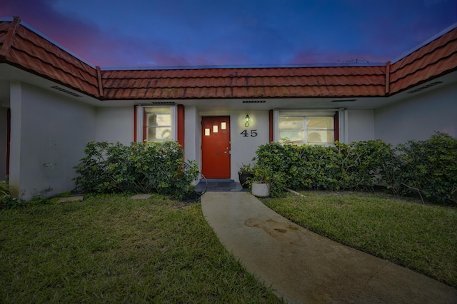 exterior entry at dusk featuring a yard