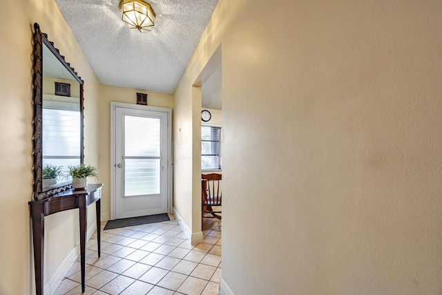 doorway to outside with light tile patterned floors and a textured ceiling