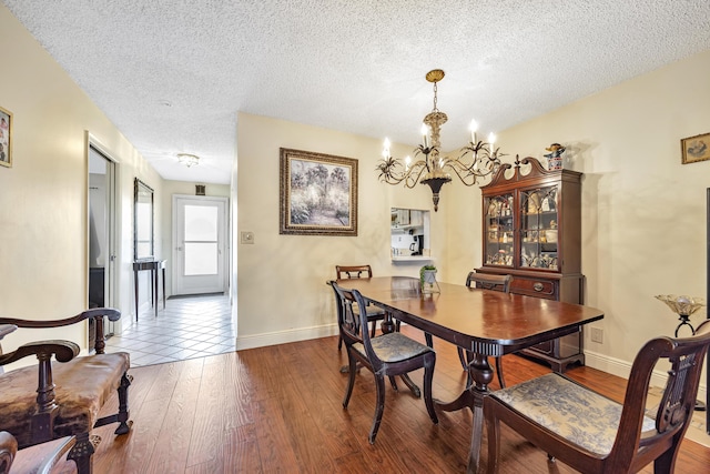 dining area featuring hardwood / wood-style floors, a textured ceiling, and a chandelier