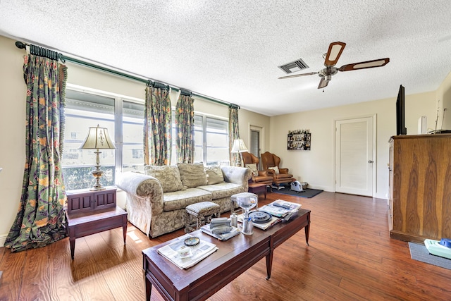 living room with hardwood / wood-style flooring, a textured ceiling, and ceiling fan