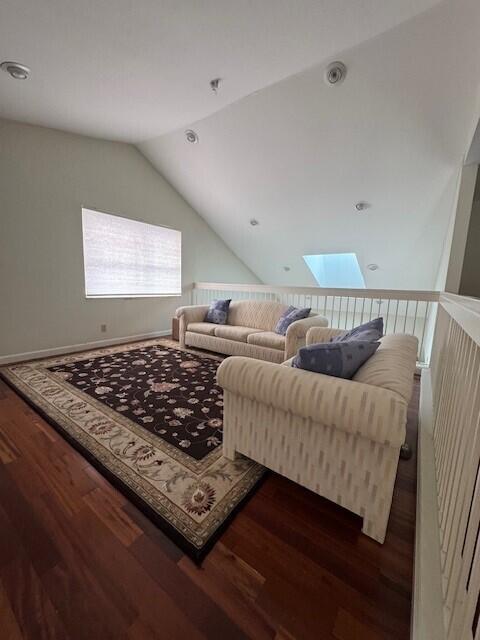 living room featuring dark hardwood / wood-style flooring and lofted ceiling with skylight