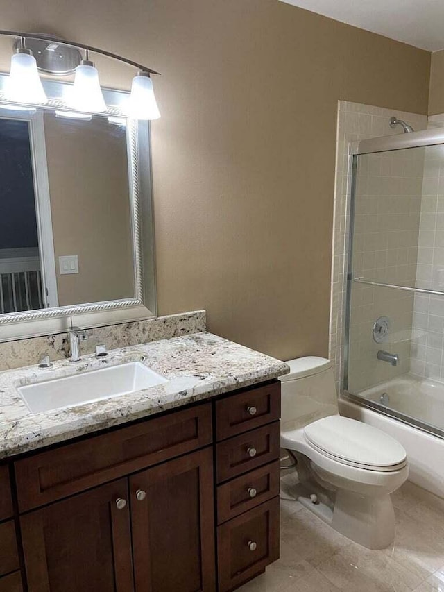 full bathroom featuring enclosed tub / shower combo, vanity, tile patterned floors, and toilet