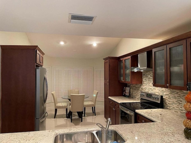 kitchen featuring sink, backsplash, light stone counters, stainless steel appliances, and wall chimney exhaust hood