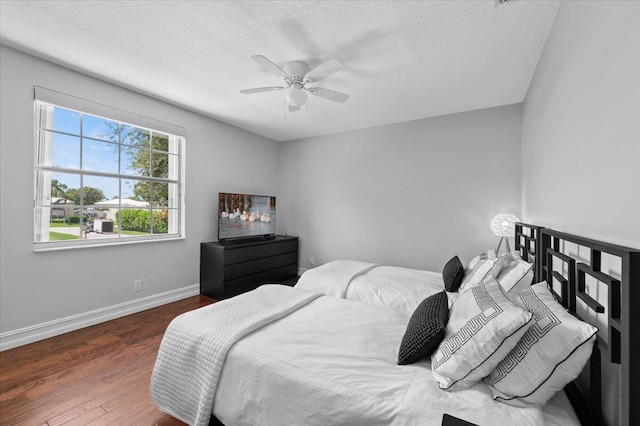 bedroom with ceiling fan, dark hardwood / wood-style floors, and a textured ceiling