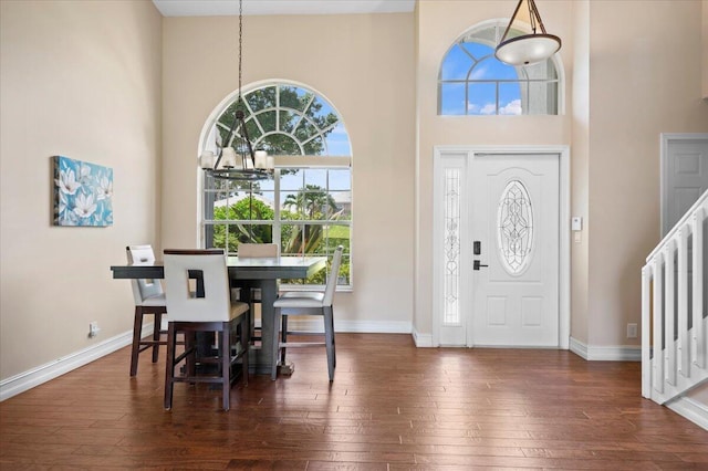 foyer featuring an inviting chandelier, a towering ceiling, and dark wood-type flooring