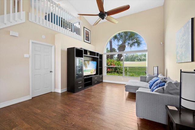 living room featuring ceiling fan, a towering ceiling, and dark hardwood / wood-style floors