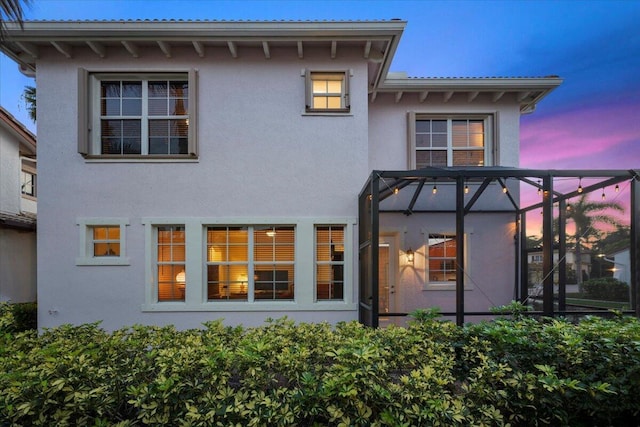 back house at dusk featuring glass enclosure