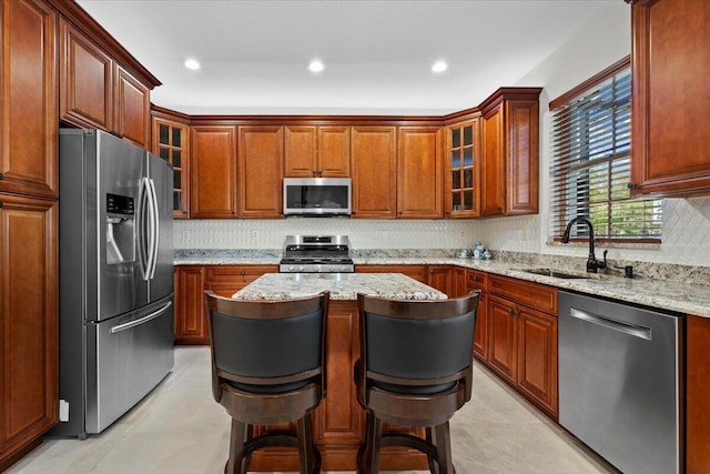 kitchen featuring sink, a breakfast bar area, a kitchen island, stainless steel appliances, and light stone countertops