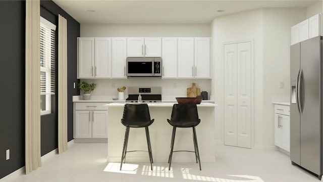 kitchen with light tile patterned floors, a breakfast bar, appliances with stainless steel finishes, a center island, and white cabinets