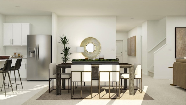 kitchen with white cabinetry, light colored carpet, and stainless steel fridge