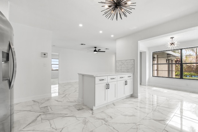 kitchen featuring ceiling fan, stainless steel fridge, kitchen peninsula, and white cabinets