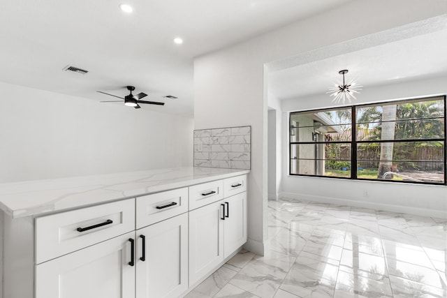 kitchen with light stone counters, ceiling fan, and white cabinets