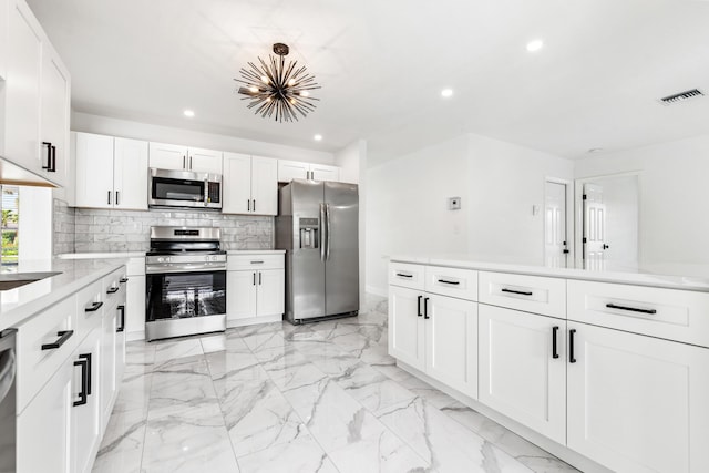 kitchen with sink, white cabinetry, stainless steel appliances, light stone countertops, and decorative backsplash