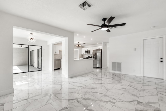 unfurnished living room featuring ceiling fan with notable chandelier and a textured ceiling