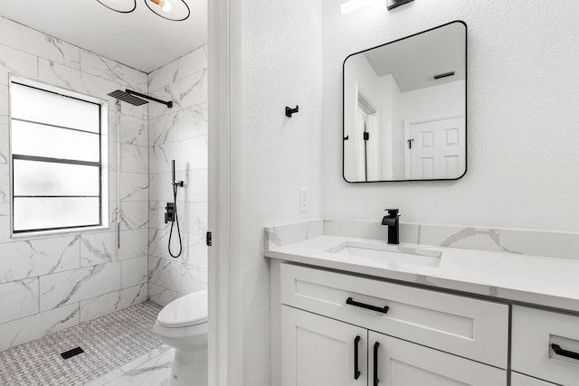 bathroom featuring tiled shower, vanity, and toilet