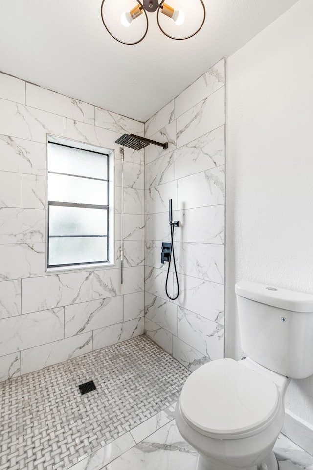 bathroom with a tile shower and toilet