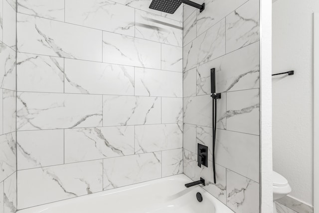 bathroom featuring tiled shower / bath and toilet