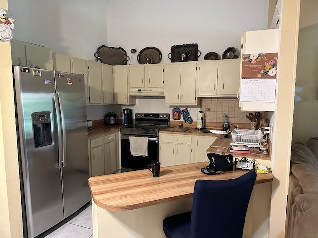 kitchen featuring electric range oven, stainless steel fridge, and cream cabinetry