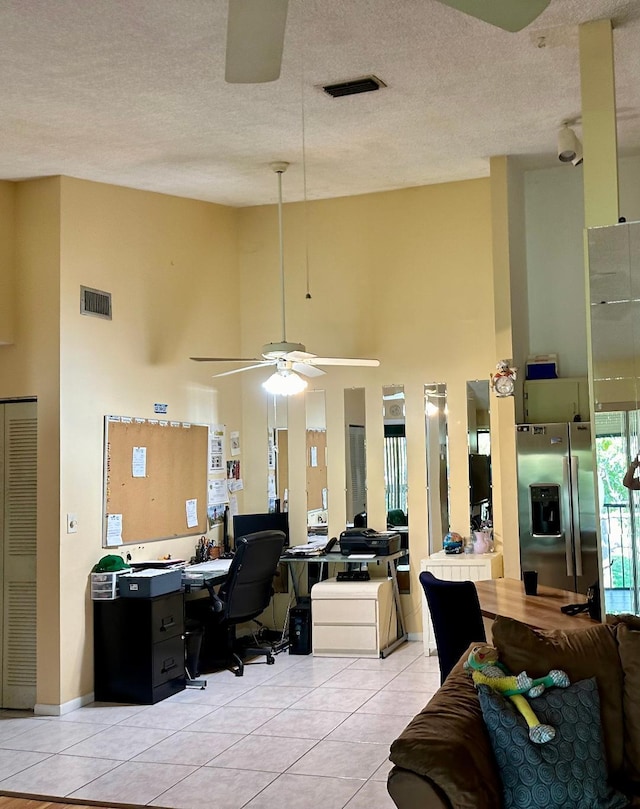 office space featuring ceiling fan, a high ceiling, a textured ceiling, and light tile patterned floors