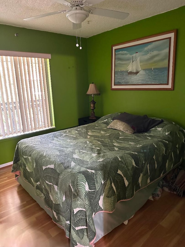 bedroom featuring ceiling fan, light hardwood / wood-style floors, and a textured ceiling