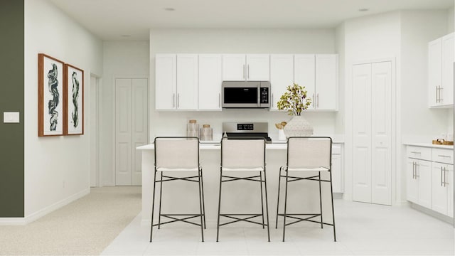 kitchen featuring a kitchen island, appliances with stainless steel finishes, a breakfast bar, white cabinetry, and light colored carpet