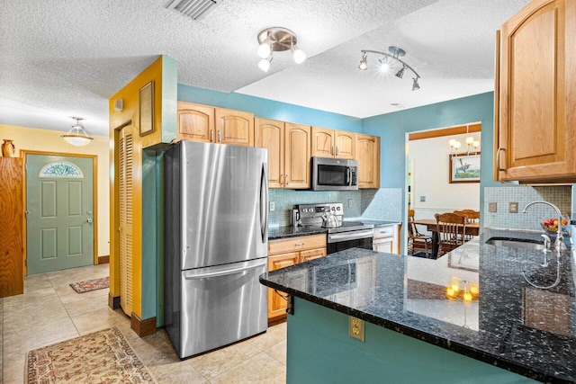 kitchen with appliances with stainless steel finishes, tasteful backsplash, sink, dark stone counters, and light tile patterned floors