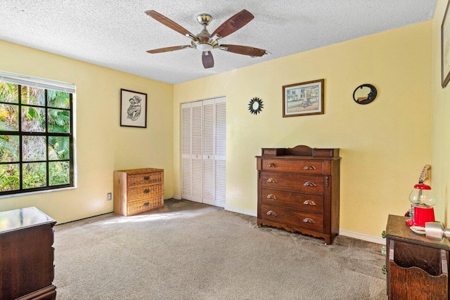 carpeted bedroom with ceiling fan, a textured ceiling, and a closet