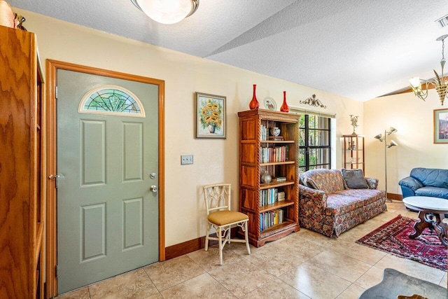 foyer with light tile patterned flooring, lofted ceiling, a chandelier, and a textured ceiling