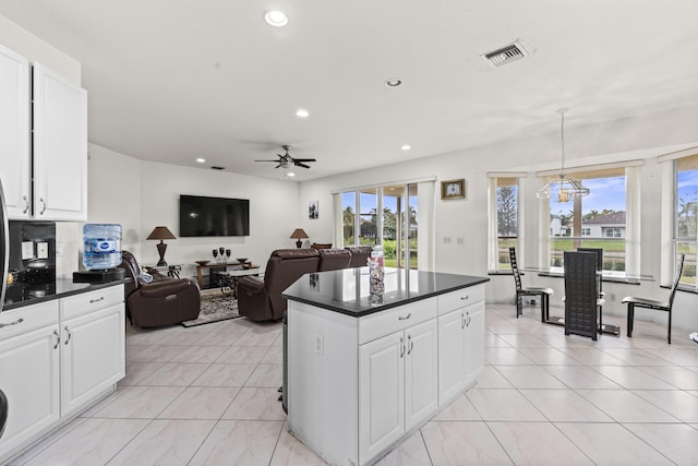 kitchen featuring pendant lighting, ceiling fan, a center island, and white cabinets