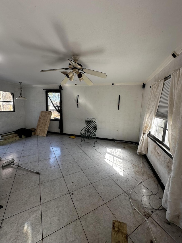 empty room featuring crown molding, light tile patterned flooring, and a ceiling fan