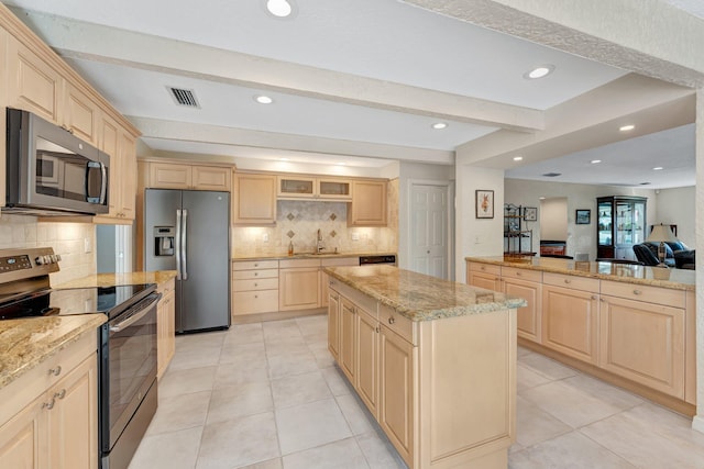 kitchen with stainless steel appliances, a center island, light brown cabinets, and beamed ceiling