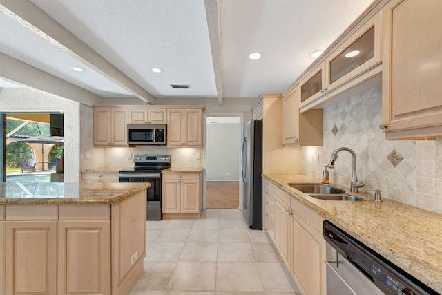 kitchen featuring appliances with stainless steel finishes, sink, light stone countertops, light brown cabinets, and beam ceiling