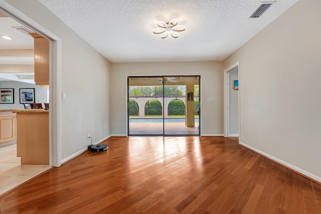 spare room with a textured ceiling and light hardwood / wood-style floors