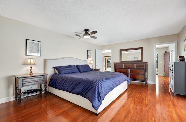 bedroom with ceiling fan, wood-type flooring, and a textured ceiling