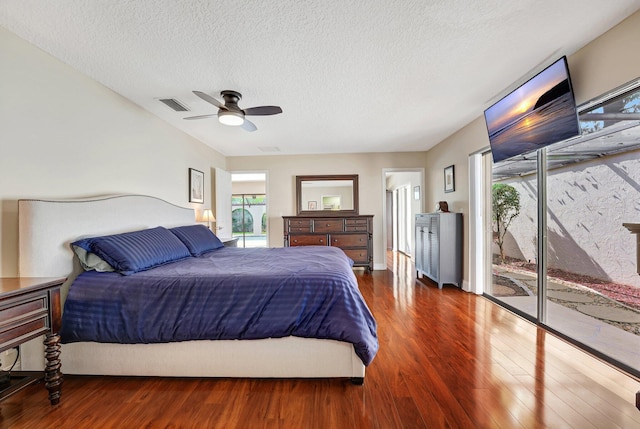 bedroom with dark hardwood / wood-style flooring, access to exterior, a textured ceiling, and ceiling fan