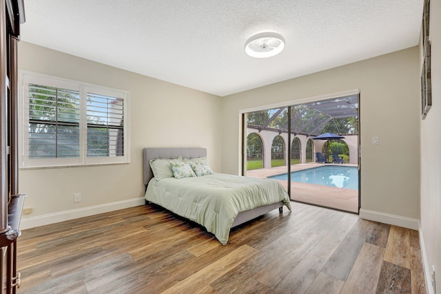 bedroom with hardwood / wood-style floors, a textured ceiling, and access to outside