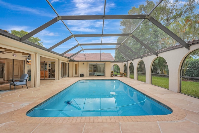 view of swimming pool with ceiling fan, a lanai, and a patio area