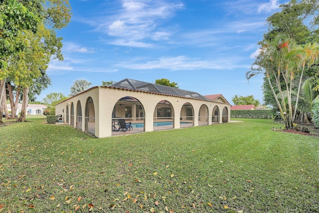 back of house with a lanai and a lawn