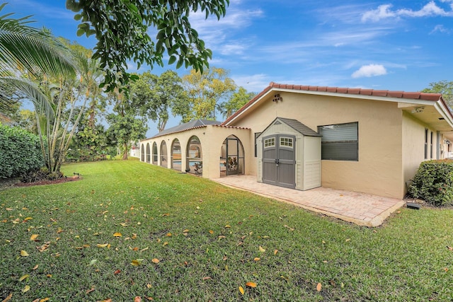 rear view of house featuring a yard and a storage unit