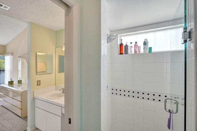 bathroom featuring vanity, a textured ceiling, and walk in shower