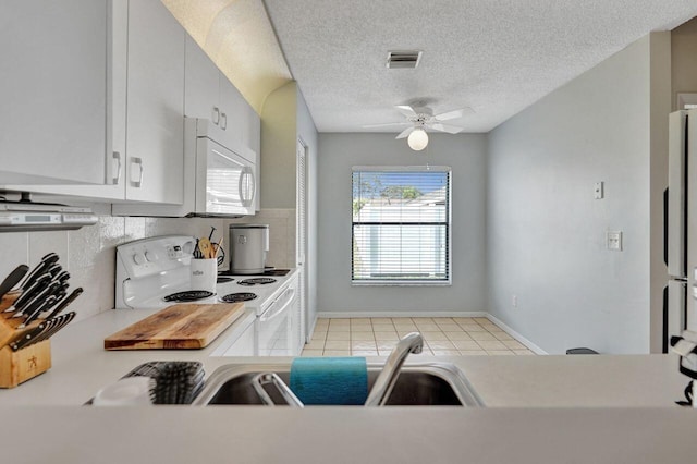 kitchen featuring white appliances, a textured ceiling, light tile patterned floors, ceiling fan, and backsplash