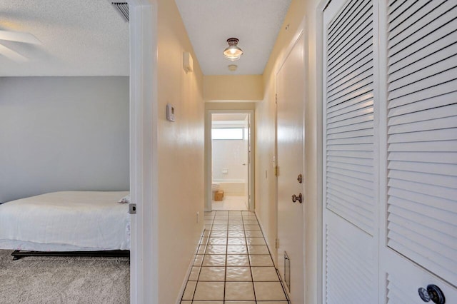 corridor featuring light tile patterned floors and a textured ceiling